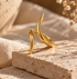 Reneax and Company minimalist gold-tone spiral wrap ring with a polished finish resting on a textured stone block.