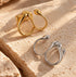 Reneax and Company sculptural double finger rings in polished gold and silver tones on a textured stone surface.