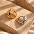 Reneax and Company gold and silver molten-style sculptural statement rings resting on a textured stone block.