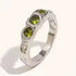 Reneax and Company three stone statement ring with a molten silver texture and three round-cut green gemstones.